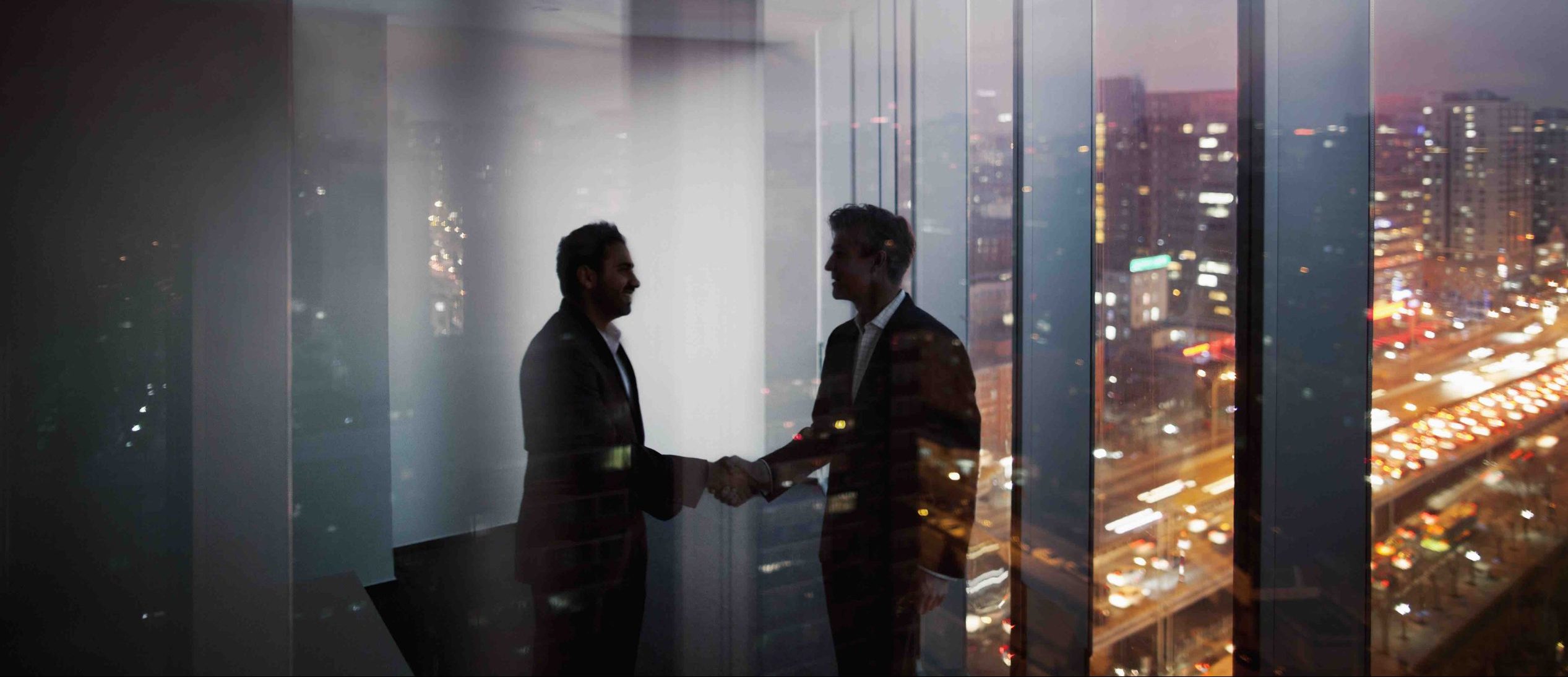 Businessmen shaking hands in office at night